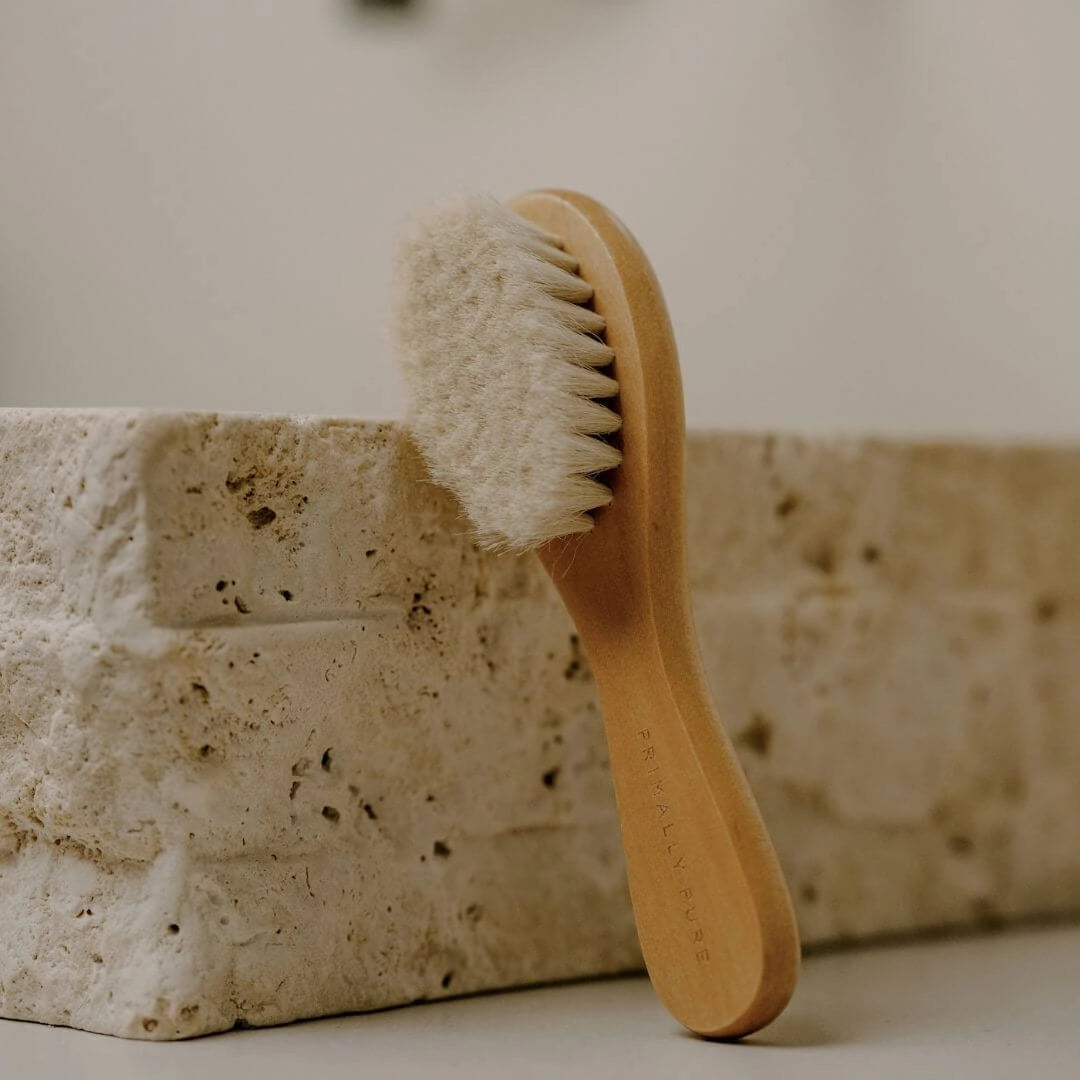 Wooden Primally Pure Facial Dry Brush Brush with soft bristles against a stone wall background Wellness Tools Collection By Primally Pure Skincare
