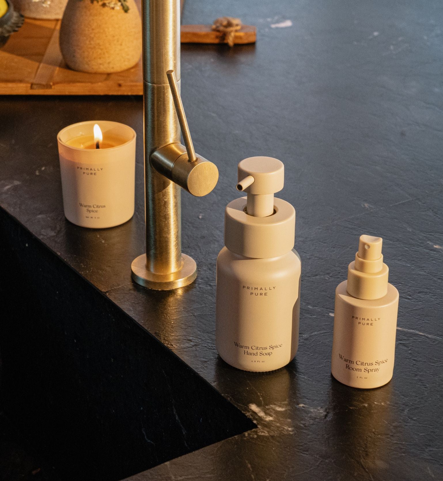 Primally Pure Warm Citrus Spice Hand Soap, Room Spray and Candle near sink in kitchen