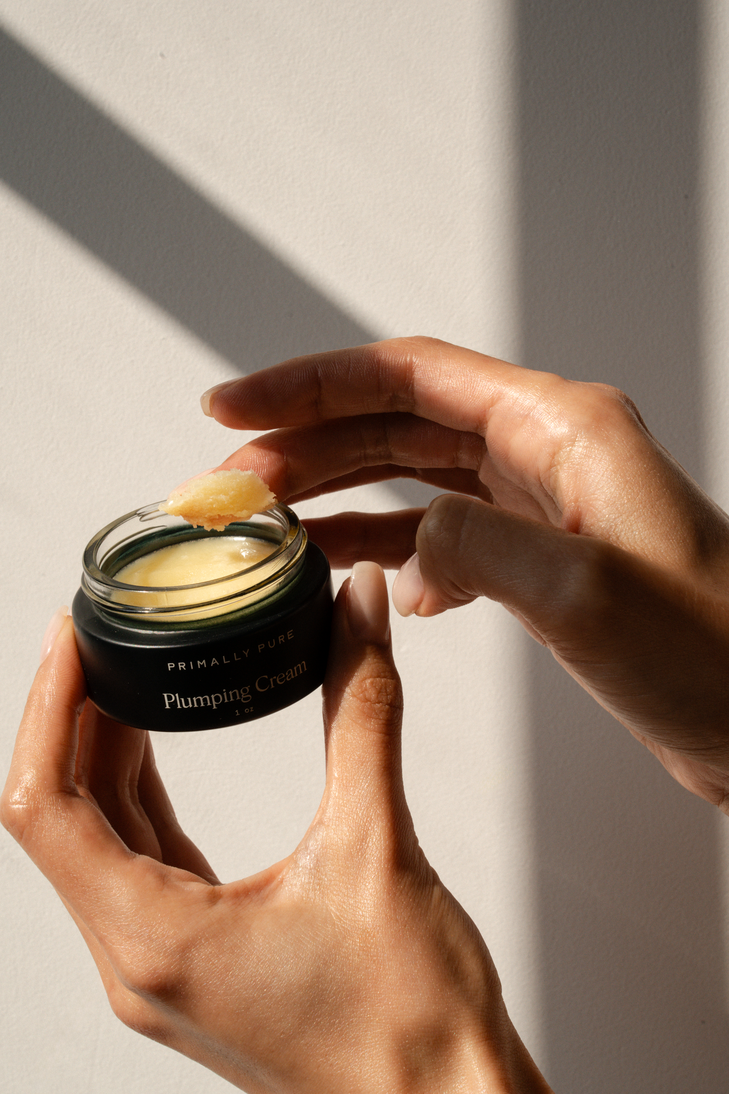 Primally Pure Plumping Cream on a woman's finger. Tallow-Based Face Cream for plumping and hydrating skin.