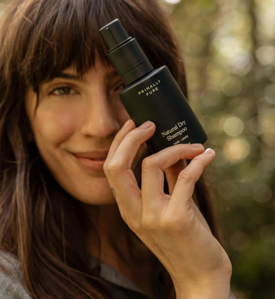 Woman holding Primally Pure Dry Shampoo Dark Locks Natural Dry Shampoo outdoors