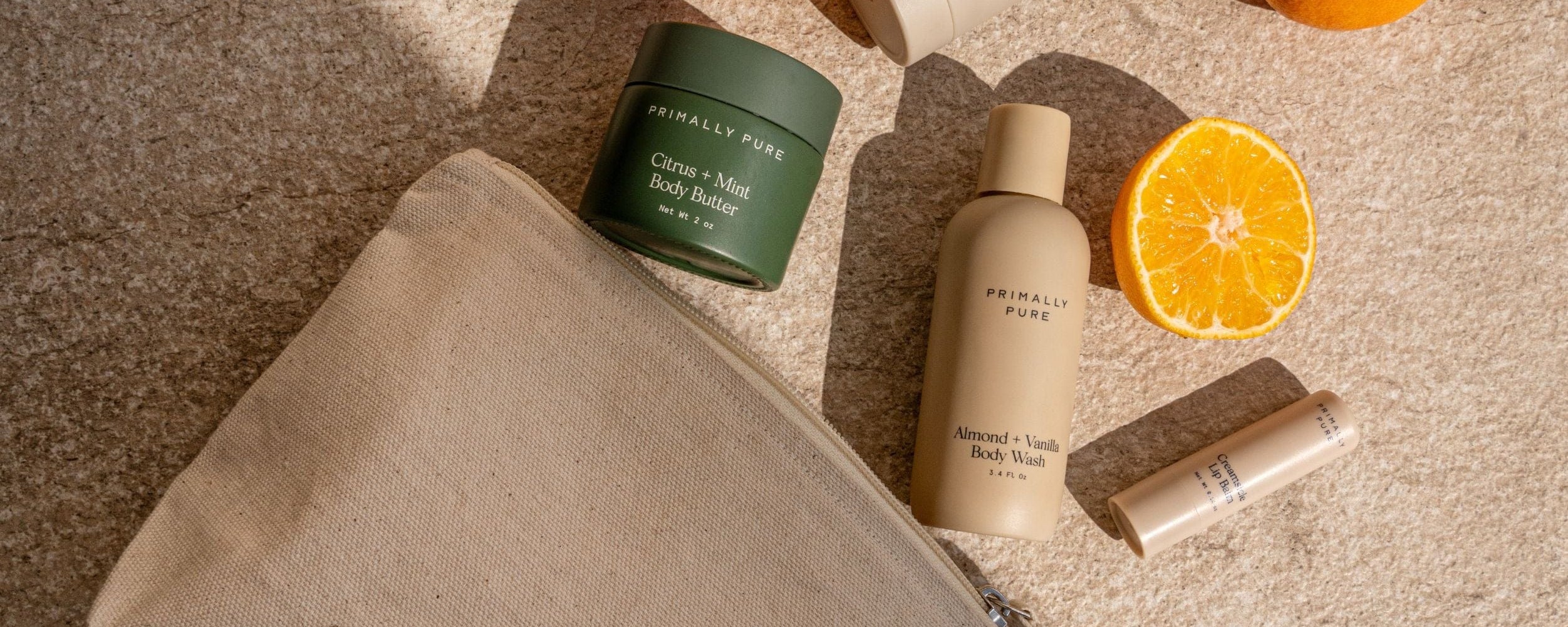 Primally Pure Cosmetic bag and travel sized skincare products on a checkered towel with 'Soil to Skin' tote branding.