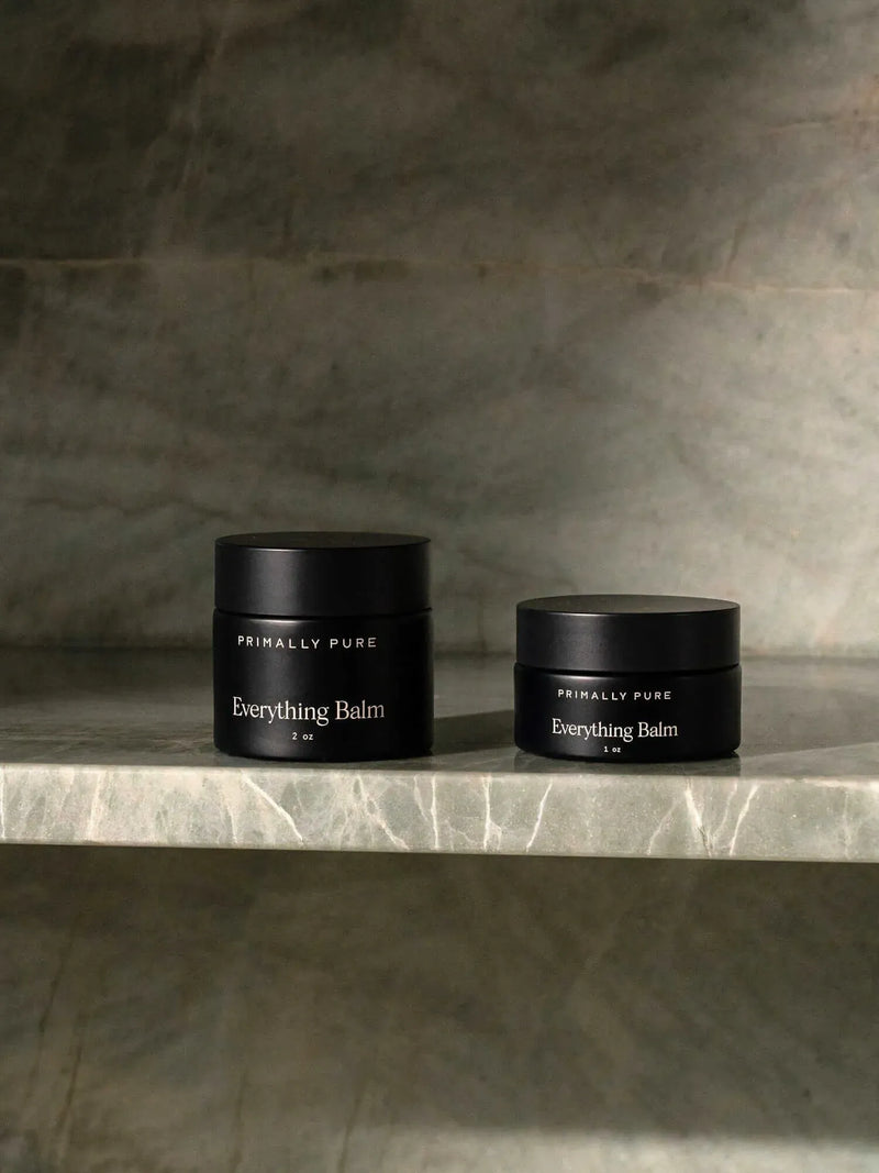 Two jars of Primally Pure Everything Balm, a tallow-based multi-purpose moisturizer, in 1oz and 2oz sizes displayed on a marble shelf.