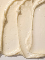 Close-up texture of creamy vanilla body butter spread on a surface.