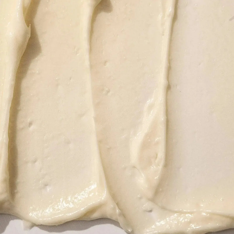 A close-up texture shot of Almond Vanilla Body Butter, Primally Pure Best-Selling Body Butter. A creamy off-white Body Butter, showing smooth swirled strokes and a glossy finish.