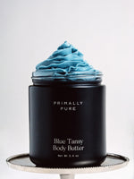 Black Jar of Primally Pure Blue Tansy on a white background showing the butter-like texture of Blue Tansy Body Butter
