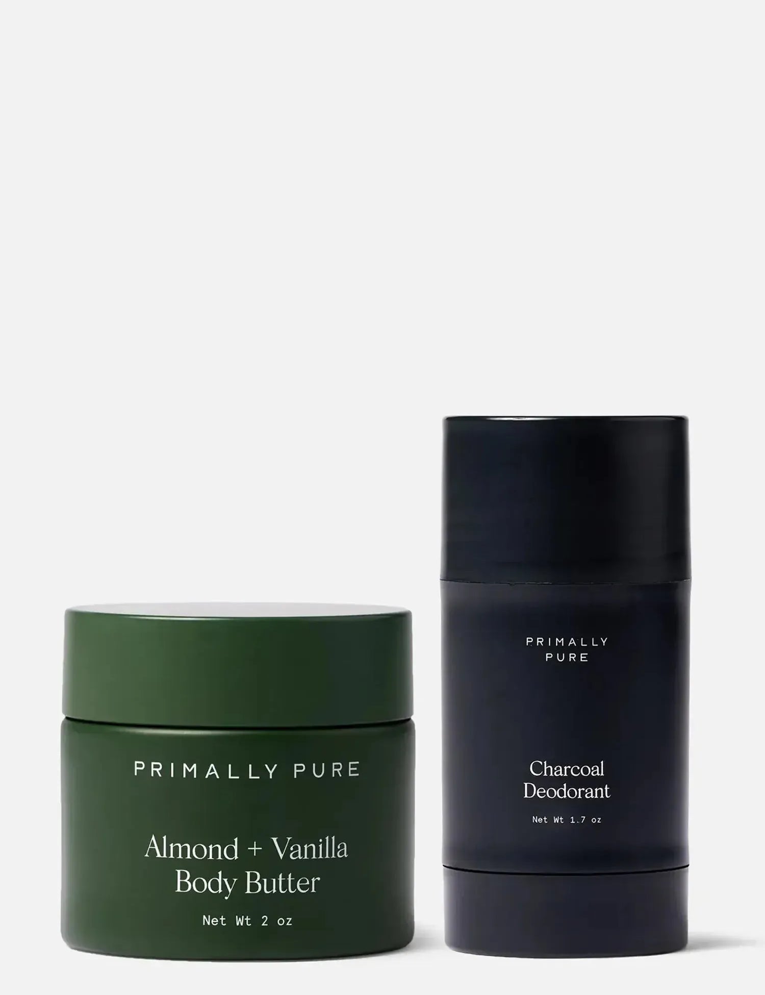 Green jar of mini Almond + Vanilla Body Butter and black tube of Charcoal Deodorant by Primally Pure on a white background.