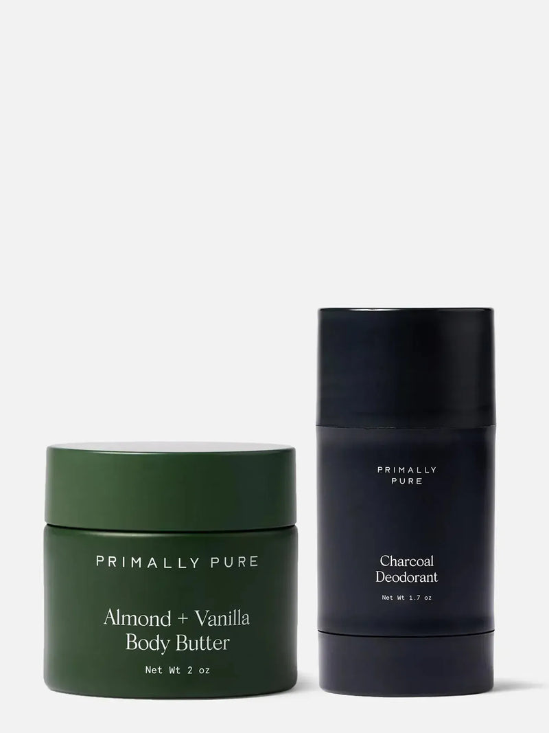 Green jar of mini Almond + Vanilla Body Butter and black tube of Charcoal Deodorant by Primally Pure on a white background.