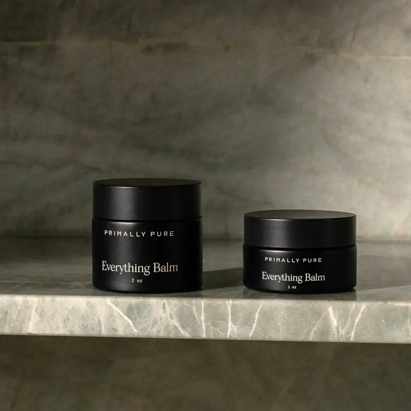 Two jars of Primally Pure Everything Balm, a tallow-based multi-purpose moisturizer, in 1oz and 2oz sizes displayed on a marble shelf.