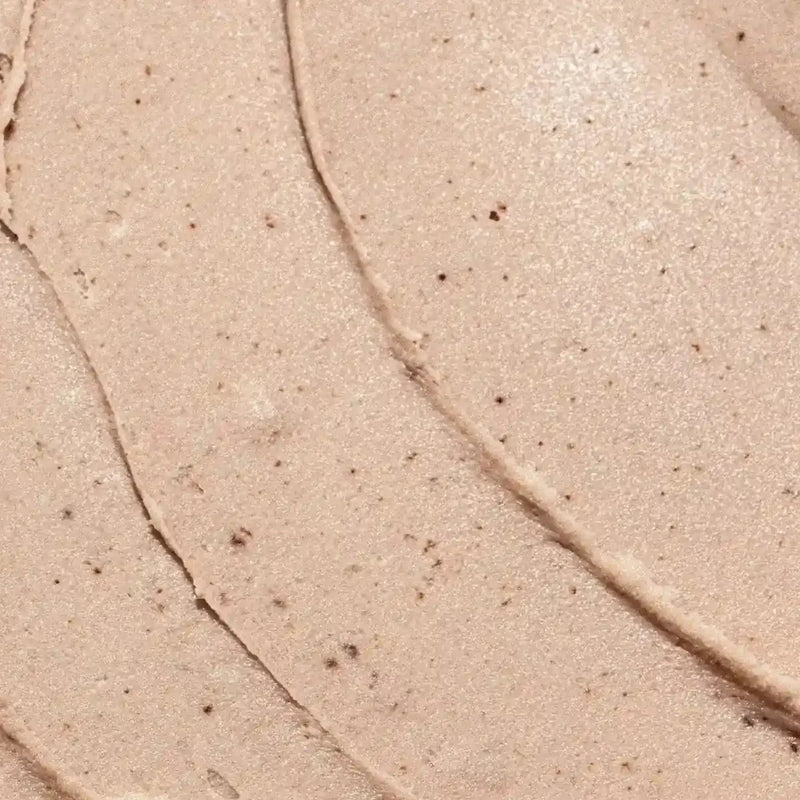 A close-up texture shot of Primally Pure Vanilla + Citrus Deodorant with fine shimmer and tiny dark specks, swirled in curved lines.